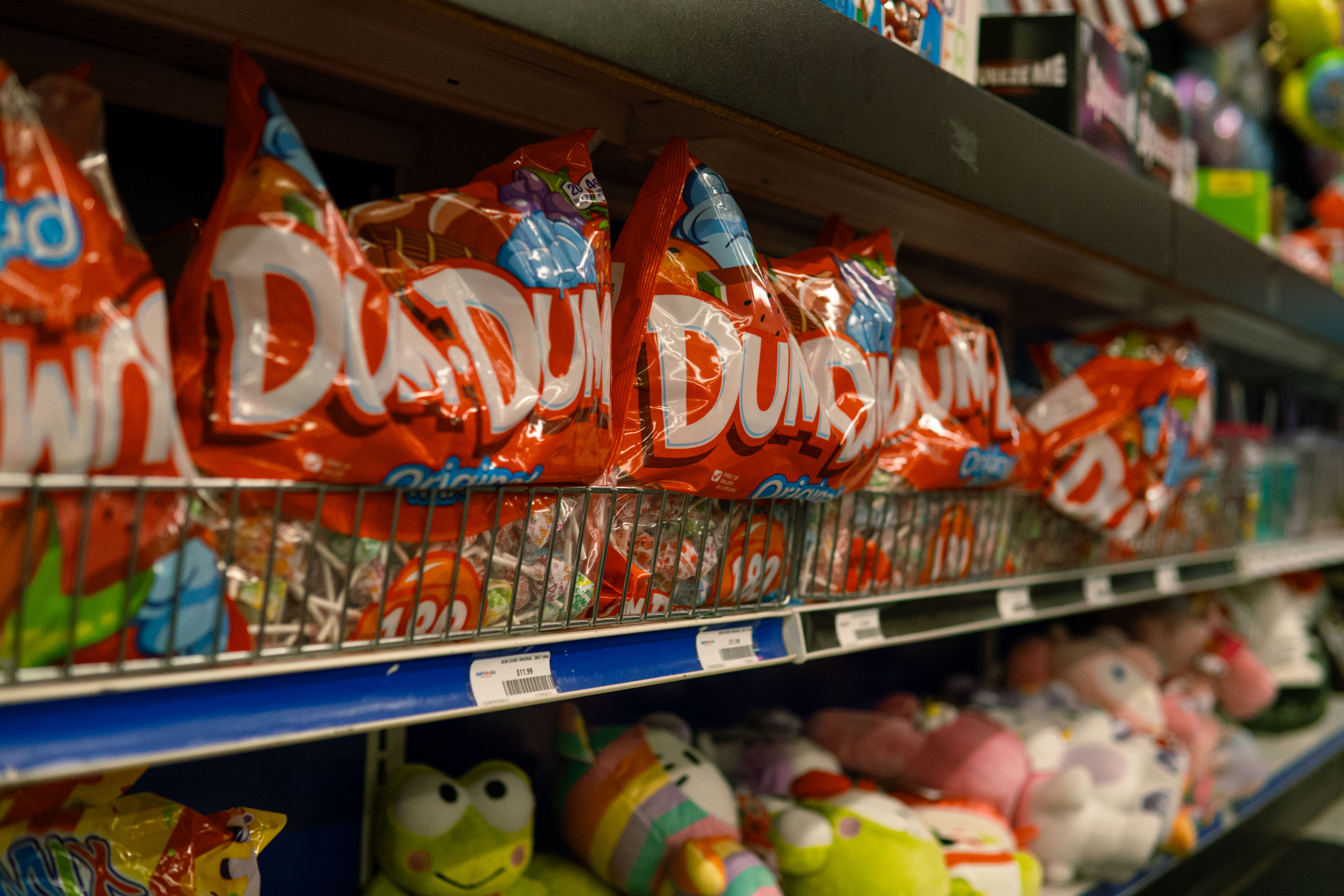 PartyWorks candy aisle shelf featuring Dum Dums lollipops and plush toys
